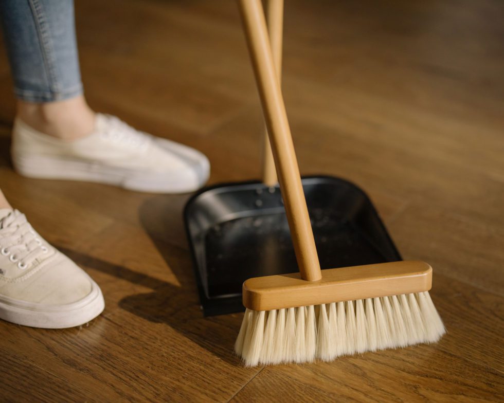 A person sweeping the floor with a broom and dustpan.