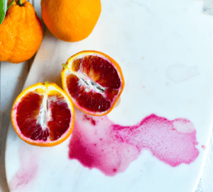 A cutting board with blood and two oranges.