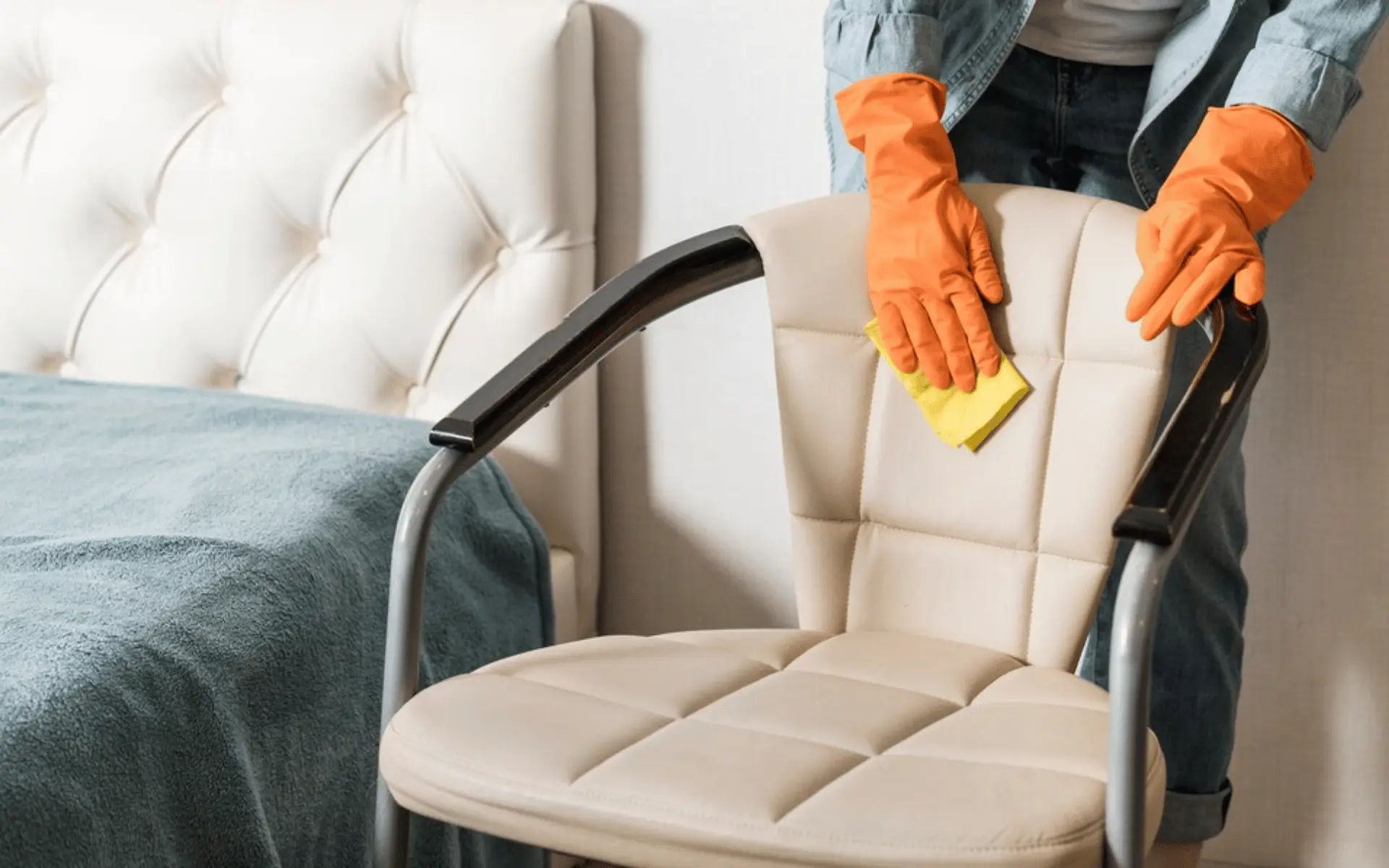 A person cleaning the back of an arm chair.