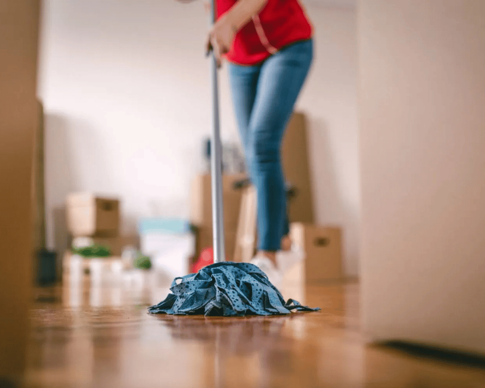 A woman is sweeping the floor with her mop.