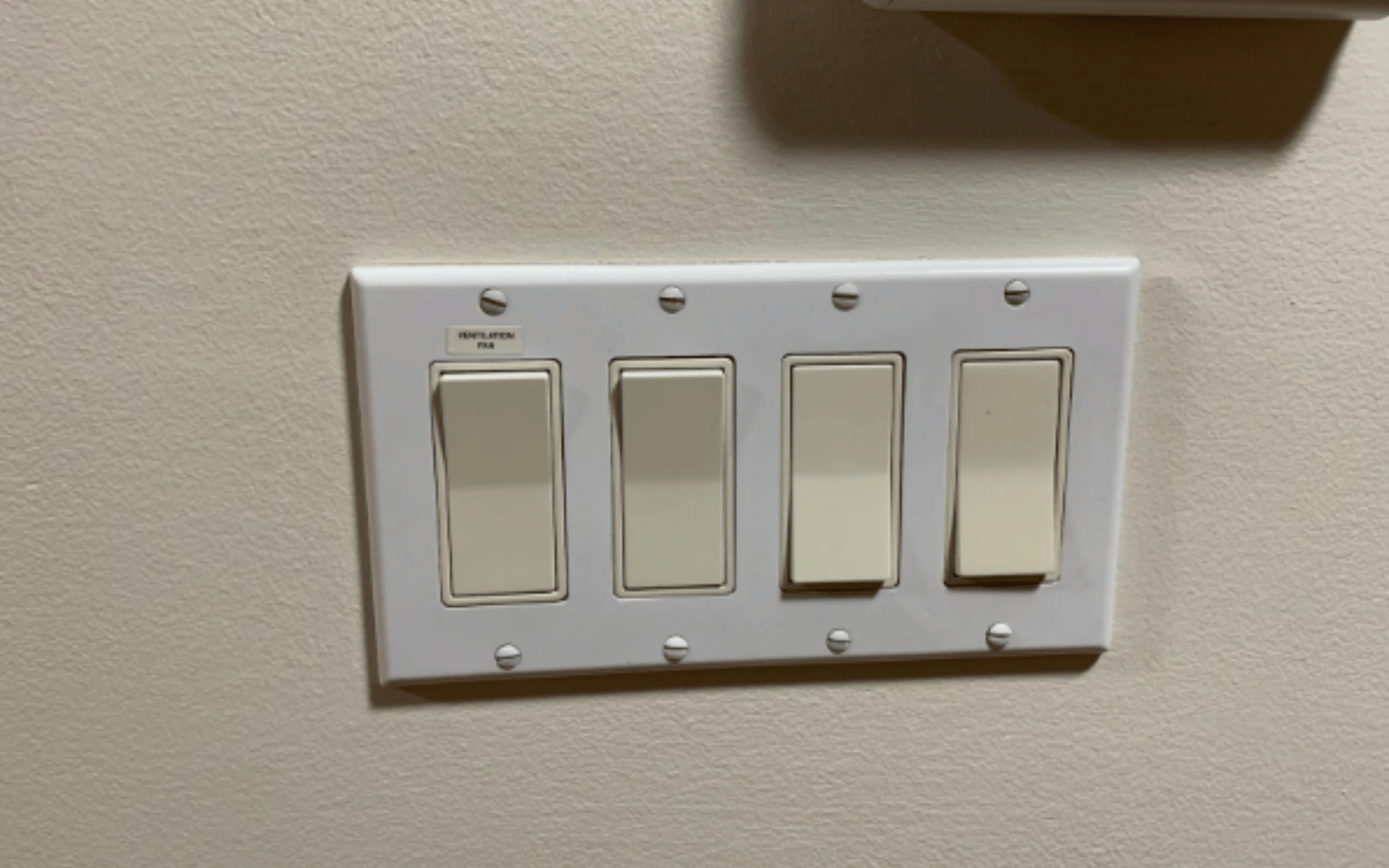 A four light switch mounted on the wall.