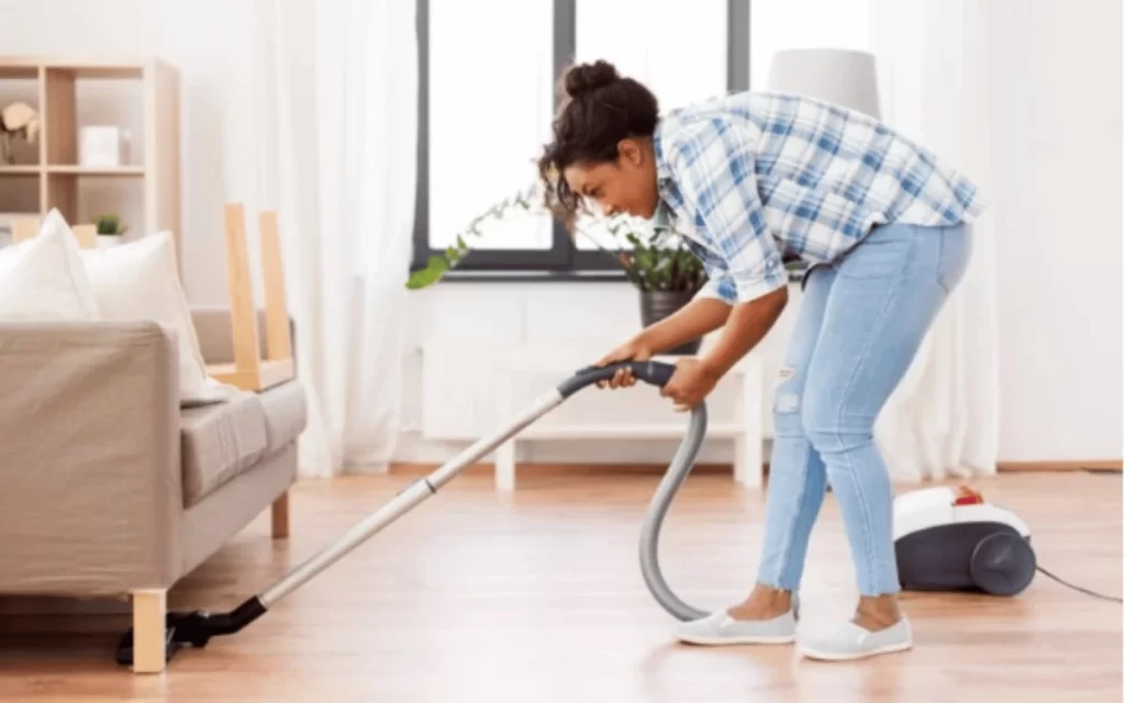 A woman is vacuuming the floor in her living room.