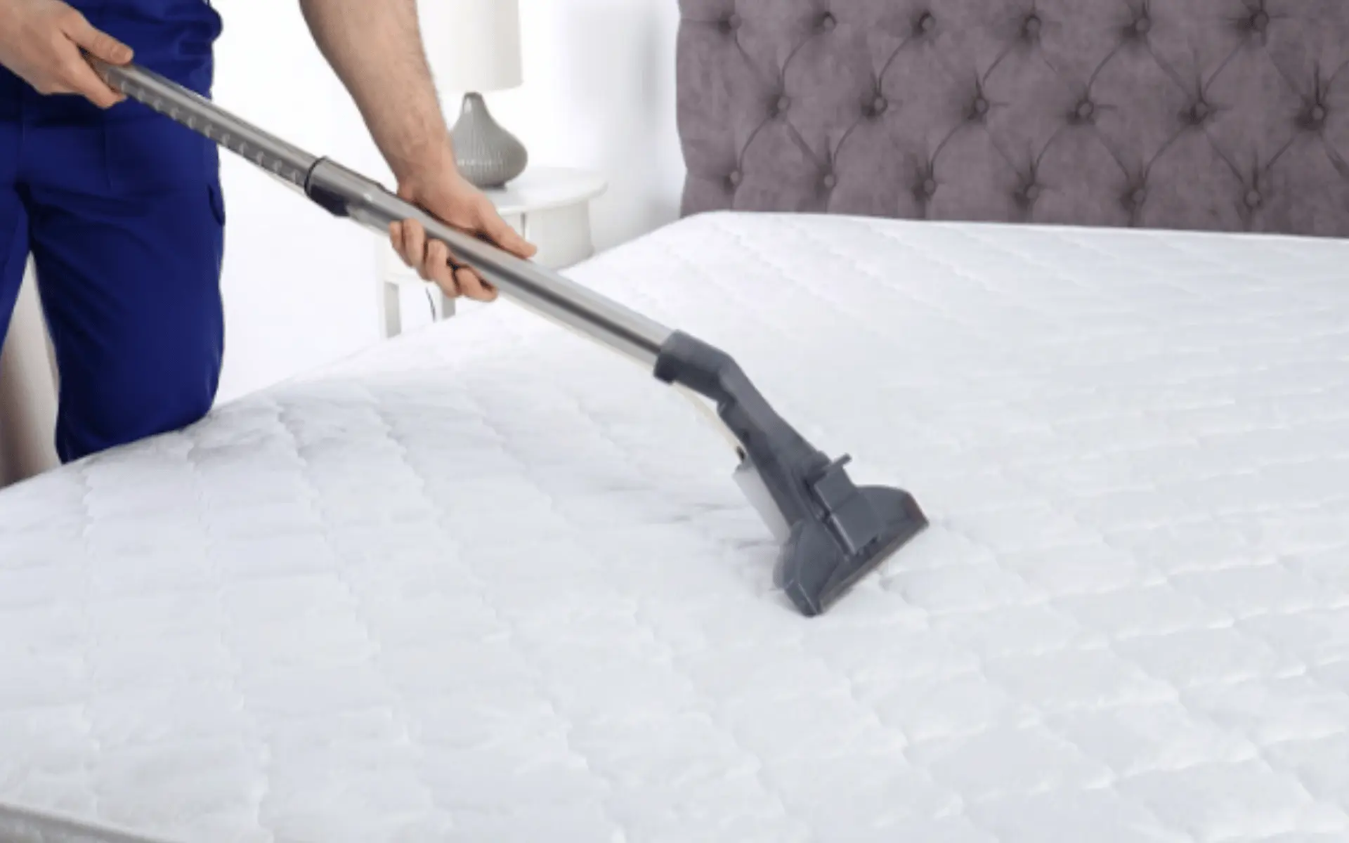 A person using a vacuum to clean the mattress.