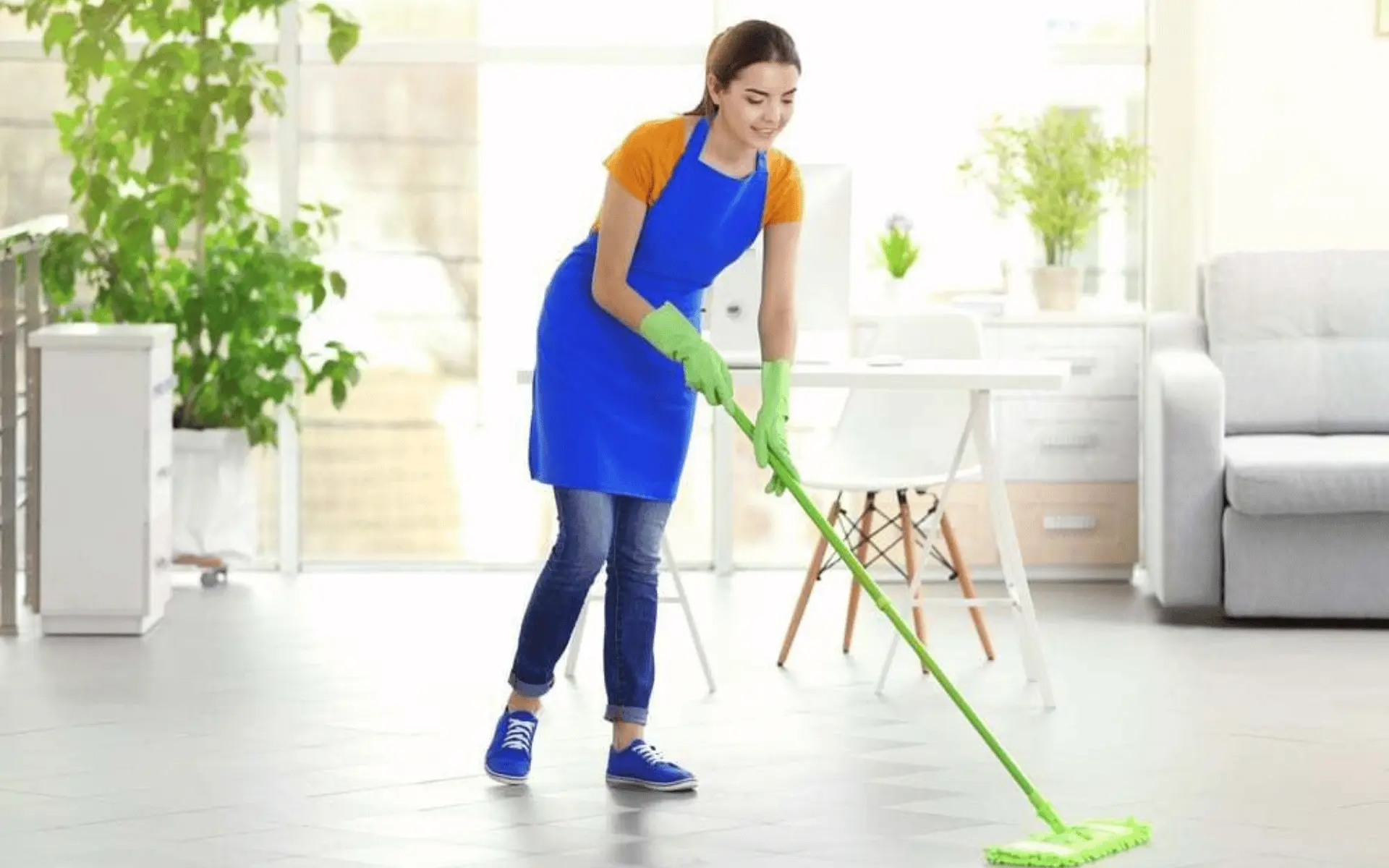 A woman in an apron is using a mop